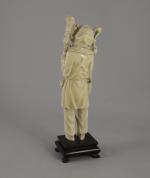 OKIMONO en ivoire représentant un personnage tenant un bâton. Japon,...