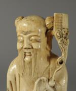OKIMONO en ivoire sculpté figurant un personnage à la longue...
